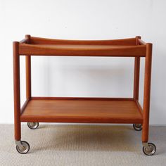 a wooden serving cart with wheels on carpeted floor