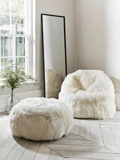 a white bean bag chair and ottoman in front of a large mirror on the floor