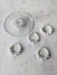 three wine glasses sitting next to each other with beaded name charms on the bottom