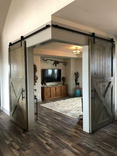 an open barn door leading to a living room with a television on the far wall