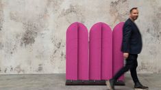 a man walking past a purple sculpture in front of a wall