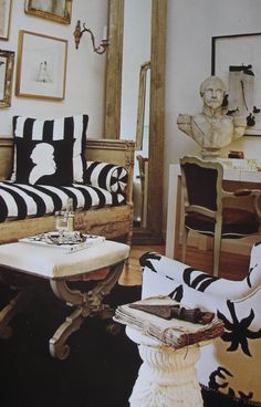 a living room with black and white decor on the walls, chairs and tables in front of a mirror