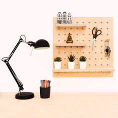 a desk with a lamp, potted plants and some scissors on the shelf next to it