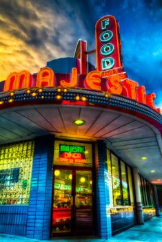 the marquee is lit up at night with colorful lights and clouds in the background