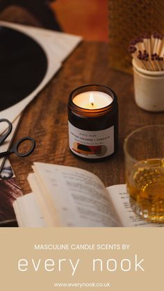 a candle sitting on top of a wooden table next to an open book and scissors