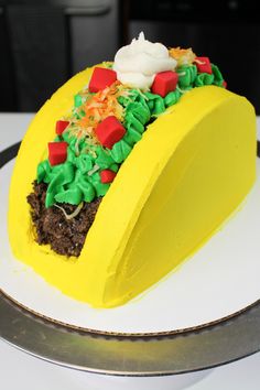 a cake shaped like a taco with toppings on it sitting on a plate