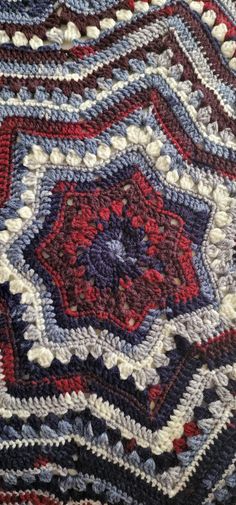 a crocheted blanket with red, white and blue designs on it's edges