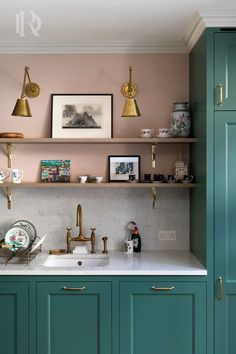 a kitchen with teal cabinets and gold pulls on the wall above the sink is filled with dishes