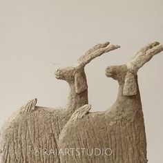 two sculptures of sheep are shown against a white background