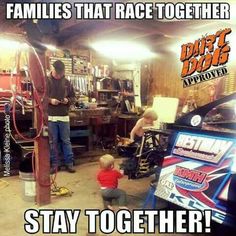 two men and a small child in a garage with an advertisement on the wall that says, families that race together stay together