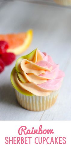 a close up of a cupcake on a plate with fruit in the background and text overlay reading rainbow sherbet cupcakes