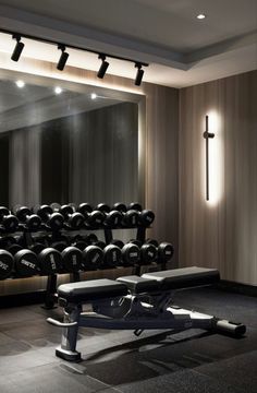 an empty gym with rows of dumbs and benches in front of a cross - shaped mirror