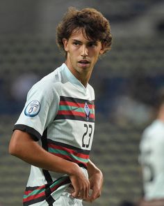 a young man standing on top of a soccer field wearing a white and black uniform