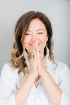 a woman with her hands together and smiling