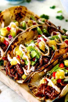 three tacos with various toppings on a cutting board