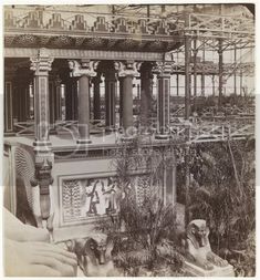 an old black and white photo of a building with statues on the outside, surrounded by trees