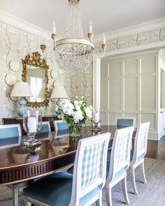 a dining room table with blue chairs and a chandelier hanging from the ceiling