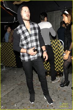 a man in a black and white checkered shirt standing next to other people at a party