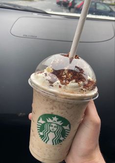 someone holding up a starbucks drink with whipped cream and chocolate shaving on top in front of a car