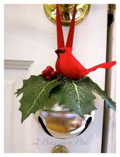 a red bird sitting on top of a glass bowl with holly and berries in it