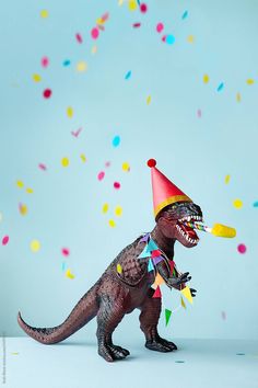 a toy dinosaur with a party hat and streamers