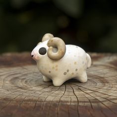 a small ceramic animal sitting on top of a wooden stump