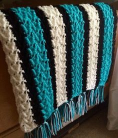 a crocheted blanket with fringes on it sitting on a bed next to a pillow