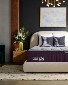 a purple mattress sitting on top of a white bed in a room with black walls