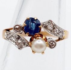 French victorian toi et moi ring 18k and platinum set with a 0.40 carat cushion cut sapphire supported by a pearl and rose cut diamonds (circa 1910) antique Magnificent and rare French goldsmith work from the 1900s  Size: 54 FR / 6.75 US Weight: 3.28g  Sapphire size: approximately 4.6 x 4.0 x 2.5 mm (estimated at 0.40 carats) Head width: 9 mm Micro scratches from use and slight wear on the sapphire Partial eagle's head hallmark (French hallmarks) and numbered 821 Visit my shop for even more anti Pearl And Sapphire Ring, Victorian Sapphire Ring With Rose Cut Diamonds For Wedding, Luxury Exquisite Pearl Ring With Rose Cut Diamonds, Victorian Sapphire Ring With Rose Cut Diamonds, Toi Et Moi Ring Napoleon, Luxury Antique Cabochon Pearl Ring, French Victorian, Eagle Head, Cushion Cut