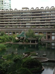 an old building with lots of windows next to a pond in the middle of it