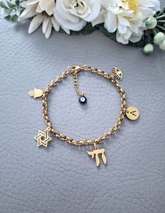 This is our beautiful personalised Jewish Braceler with Chai, Hamsa, Star of David, Lucky Eye and initial letter charms. It Makes a beautiful and thoughtful gift for your loved ones. Materials are 18k gold plated over Stainless Steel, it's hypoallergenic, waterproof and tarnish resistant.   All our items are custom made, it takes 3-5 days to get your order prepared.  The delivery date will depend on your location.  * USA - 2 - 4 weeks * Canada - 2 - 5 weeks * Europe - 2-3 weeks * Other - 2 - 4 w Symbolic Gold Bracelets With Charms, Handmade Charm Bracelet As Personalized Gift, Handmade Charm Bracelet For Personalized Gifts, Handmade Yellow Gold Charm Bracelet As A Gift, Gold Charm Bracelet With Symbolic Dangling Charms, Gold Symbolic Metal Charm Bracelet, Gold Plated Charm Bracelet For Gift, Gold Plated Dangle Charm Bracelet Gift, Yellow Gold Metal Charm Bracelet As Gift