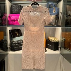 a dress and purses are on display in a store window with shelves full of handbags