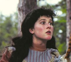 a woman with long black hair holding a rope in her hand and looking up at the sky