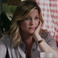 a woman sitting at a table with her hand on her chin and looking off to the side