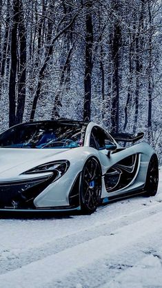 a white and black sports car parked on the side of a snow covered road in front of trees