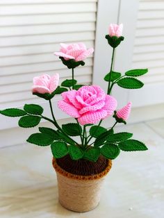 a crocheted pot with pink flowers in it