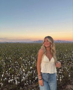 a woman standing in the middle of a cotton field at sunset with her hands on her hips