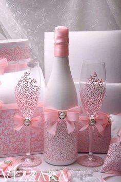 a table topped with wine glasses and bottles filled with pink ribboned bows next to white boxes