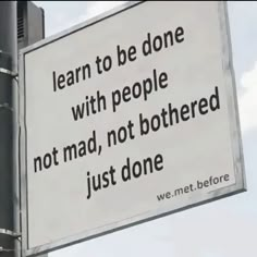 a sign that is hanging from the side of a pole in front of a cloudy sky