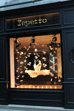 a store front window that has lights in the windows and paper birds flying around it