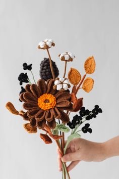 a person is holding a crocheted flower bouquet