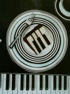 a white plate topped with chocolate cake on top of a piano keyboard and fork next to it