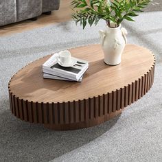 a coffee table with two books and a vase on it in the middle of a living room