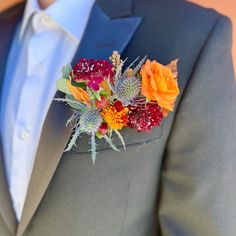 a man in a gray suit with orange and red flowers on his lapel flower