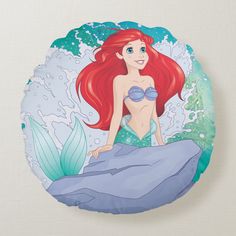 the little mermaid is sitting on top of a rock