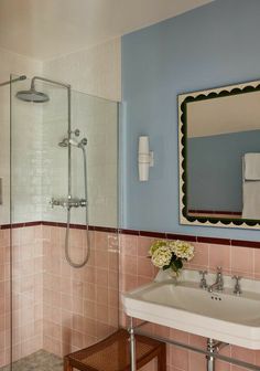 a bathroom with pink and blue walls, a white sink and a shower head mounted to the wall