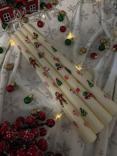 some white candles with christmas decorations on them