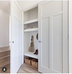 an open closet with shoes and baskets on the shelf next to it, in front of some stairs