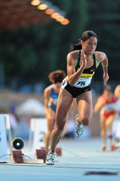 a woman running in a race with other people behind her