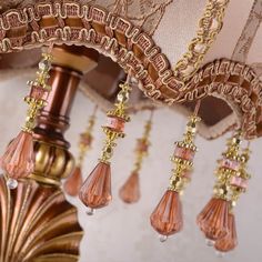 a chandelier hanging from the ceiling with pink and gold bead trimmings